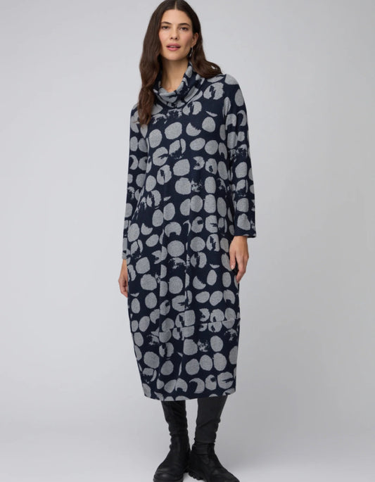 Woman wearing a long navy dress with white pattern on a white background