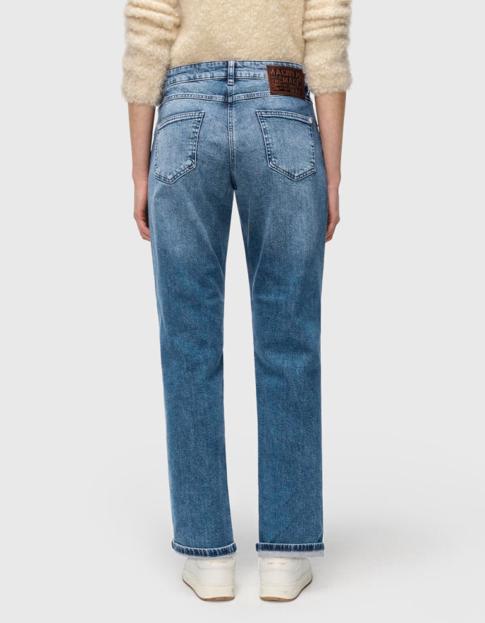 Person wearing blue jeans and a beige sweater on a white background