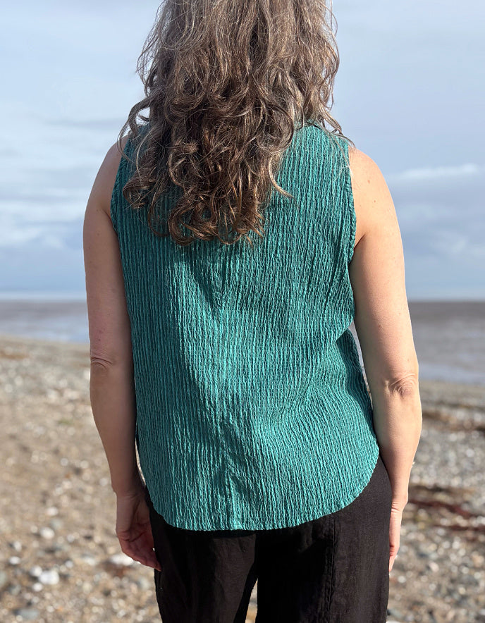 woman wearing teal sleeveless shirt on a beach