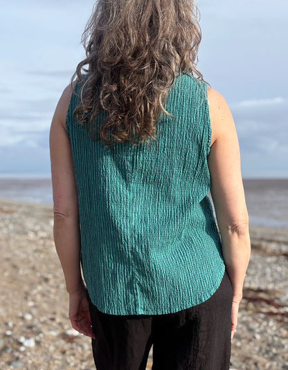 woman wearing teal sleeveless shirt on a beach