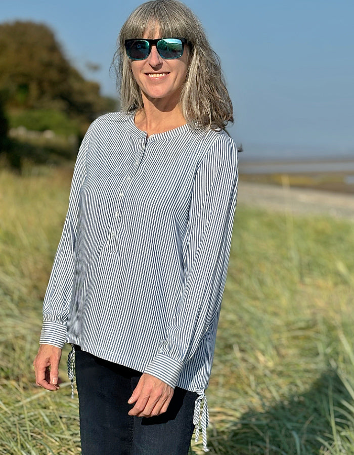 blue and white stripe blouse with half button placket fastening at the front and side drawstring tie