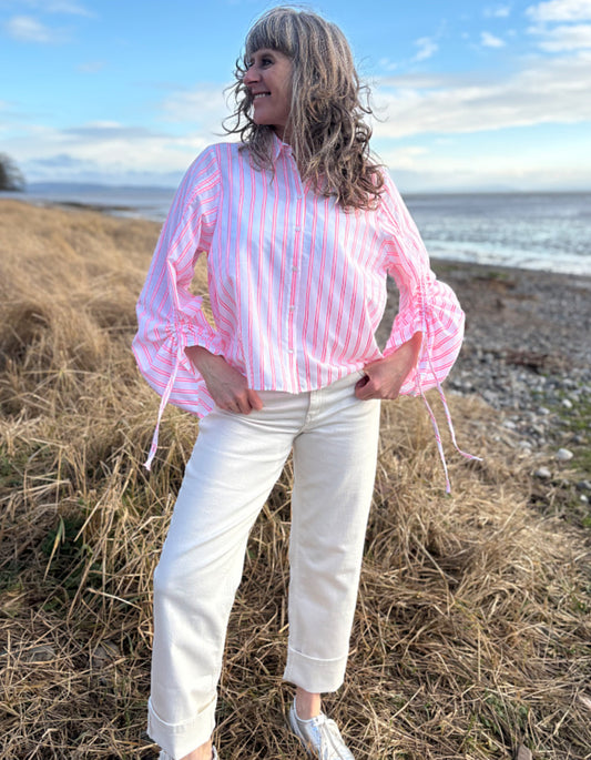 woman wearing cotton pink pion striped shirt with gathered sleeves and cream cropped jeans