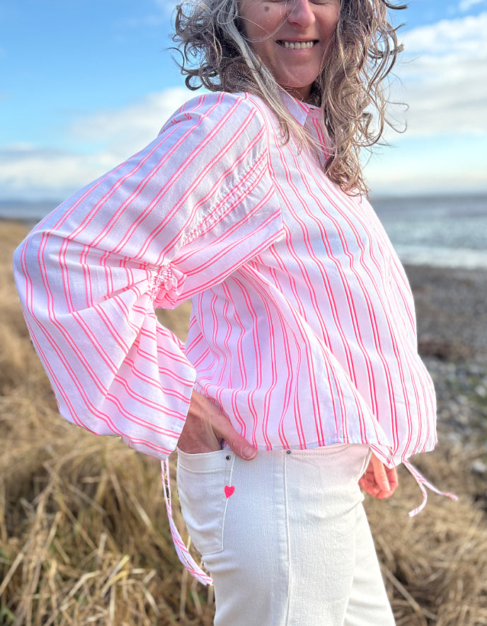 woman wearing cotton pink pion striped shirt with gathered sleeves and cream cropped jeans