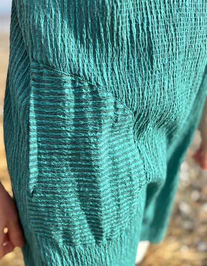 Close-up of a textured teal fabric with a hand holding it.