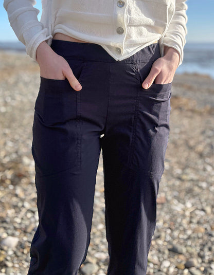 Person wearing navy pants and a light-colored shirt on a pebbly beach.