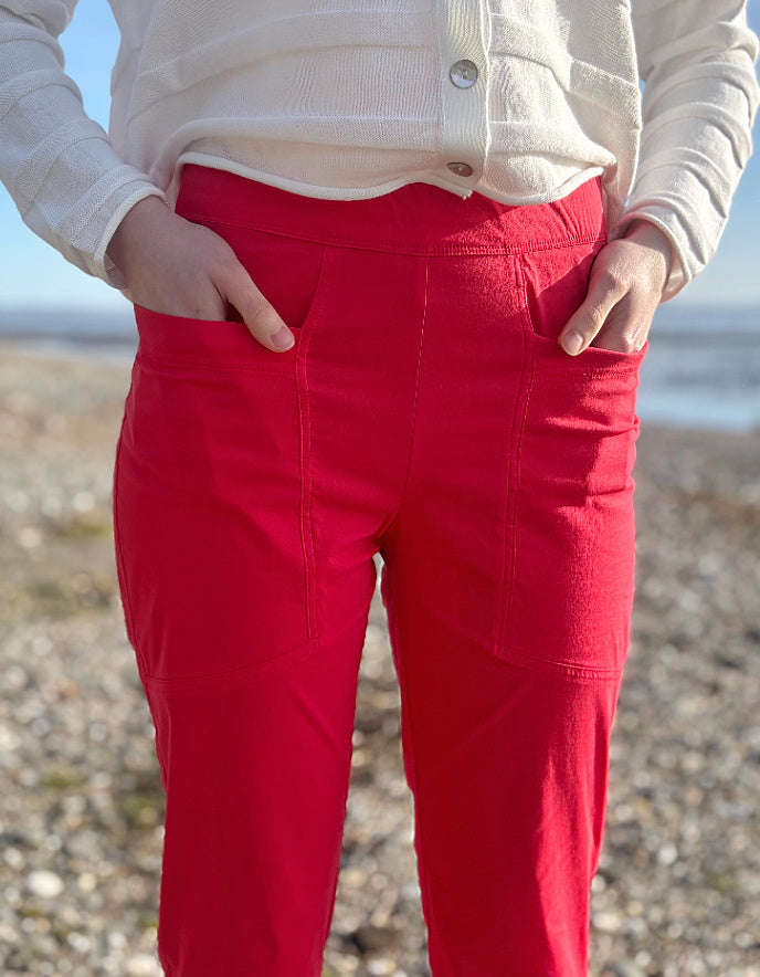Person wearing red pants and a cream jacket standing on a beach.