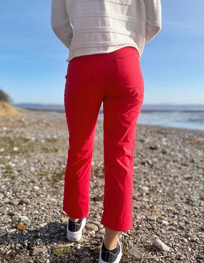 Person wearing red pants and a light-colored jacket on a pebbly beach.