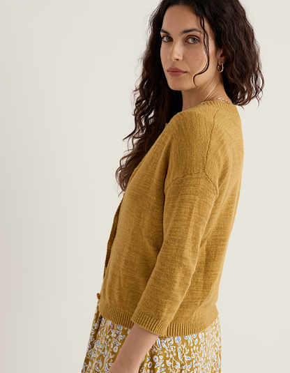 woman wearing ochre yellow coloured cotton linen cardigan with a floral dress