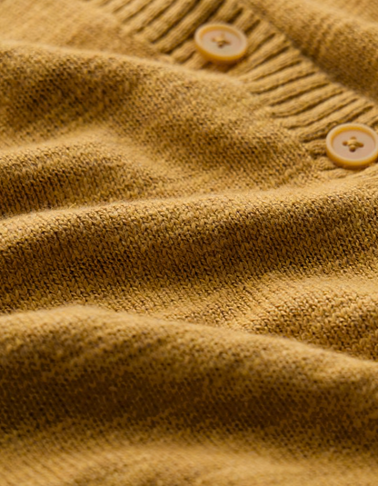 woman wearing ochre yellow coloured cotton linen cardigan with a floral dress