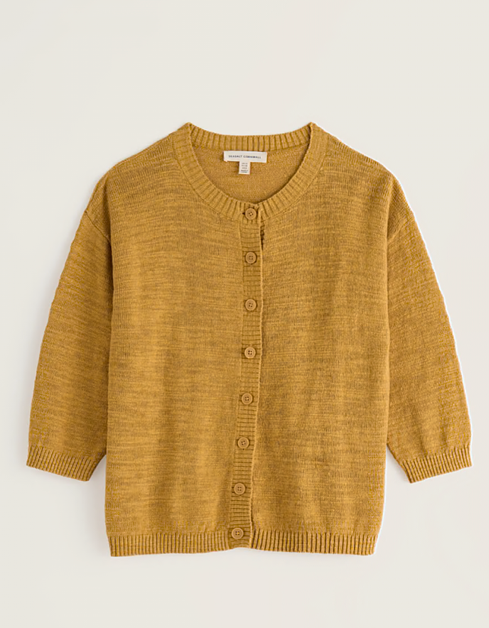 woman wearing ochre yellow coloured cotton linen cardigan with a floral dress