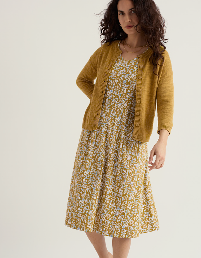 woman wearing ochre yellow coloured cotton linen cardigan with a floral dress