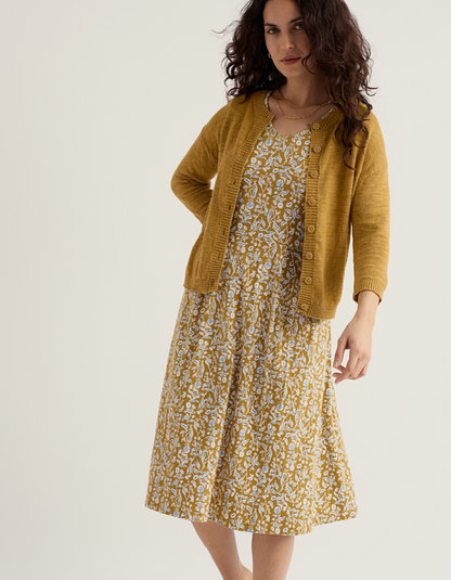 woman wearing ochre yellow coloured cotton linen cardigan with a floral dress