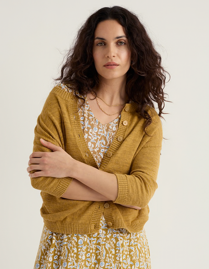 woman wearing ochre yellow coloured cotton linen cardigan with a floral dress