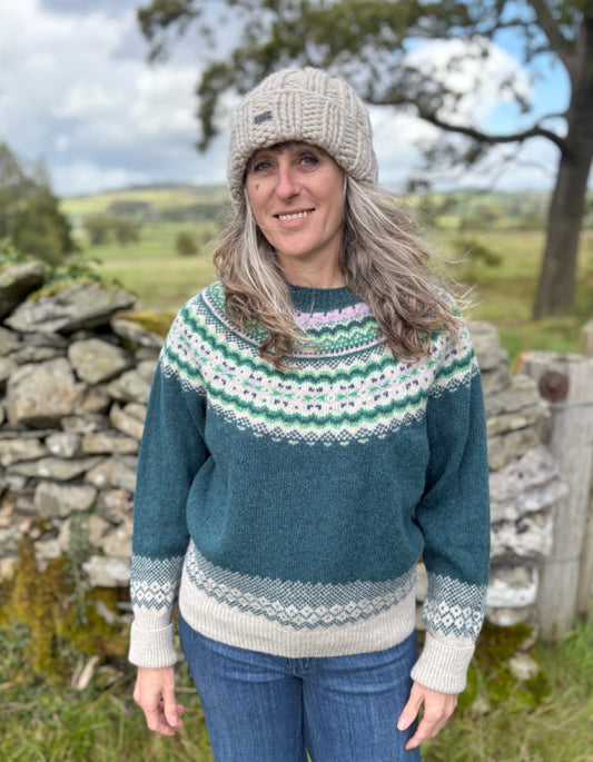 Woman wearing a teal sweater with a patterned design outdoors