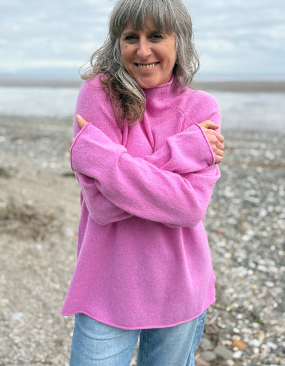 Woman wearing a pink wool merino sweater standing on a beach