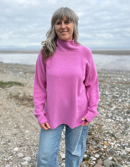 Woman wearing a pink wool merino sweater standing on a beach