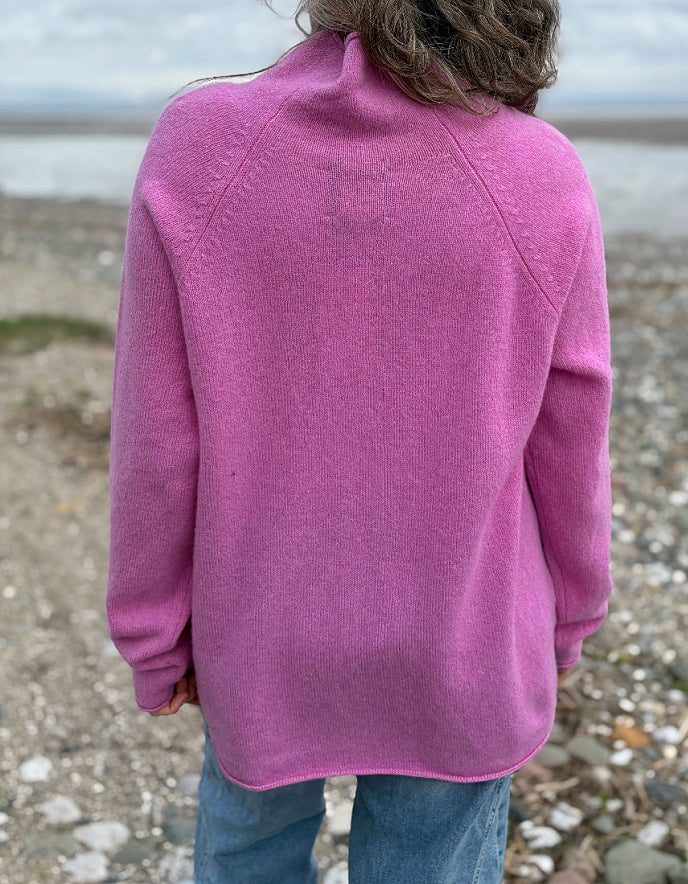 Woman wearing a pink wool merino sweater standing on a beach