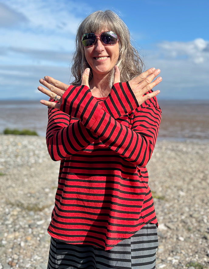 Woman wearing a red and black striped fleecy line long sleeve T shirt on a beach