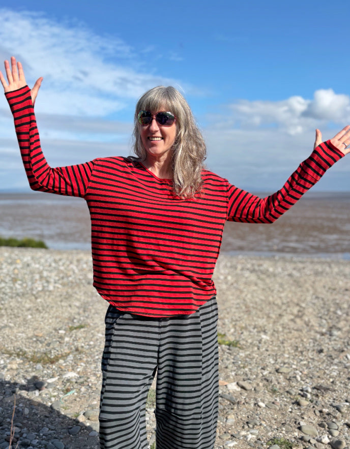 Woman wearing a red and black striped fleecy line long sleeve T shirt on a beach