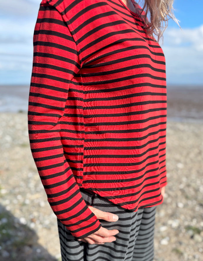 Woman wearing a red and black striped fleecy line long sleeve T shirt on a beach