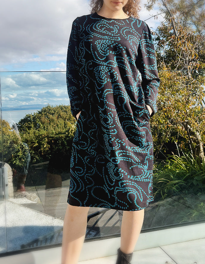 knee length black dress with pockets and blue geometric pattern