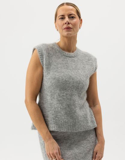 Woman wearing a gray knitted sleeveless top against a white background