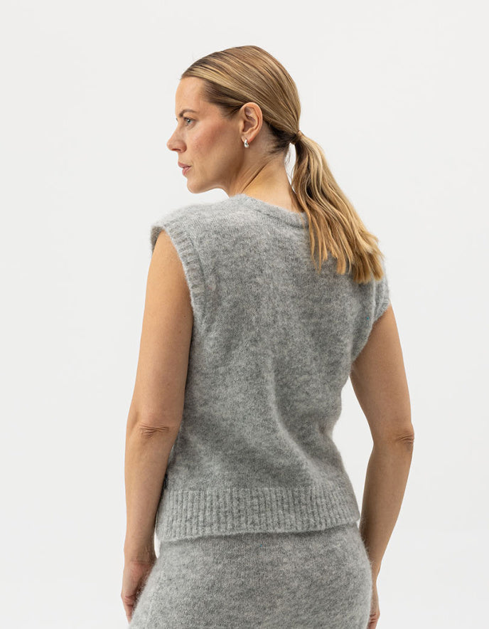 Woman wearing a gray knitted vest against a white background
