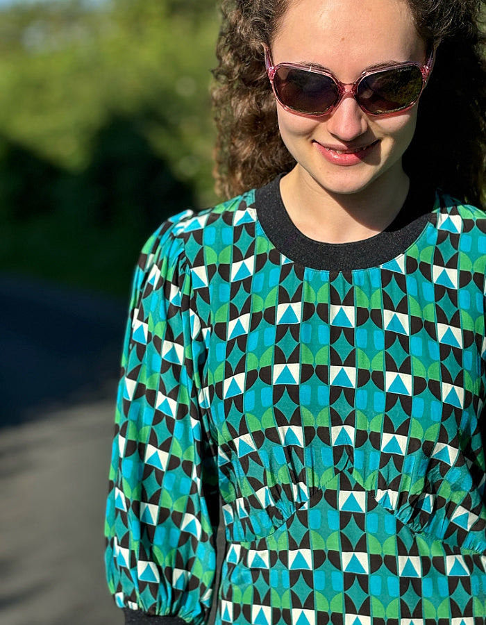 midi length dress with black and green and blue geo print and blouson sleeves