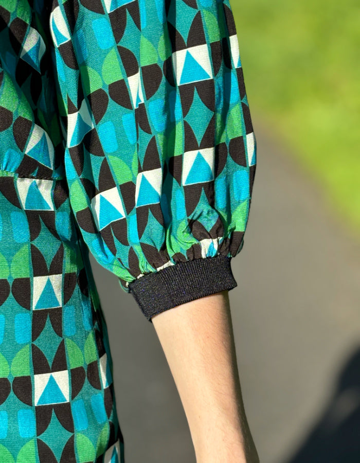 midi length dress with black and green and blue geo print and blouson sleeves