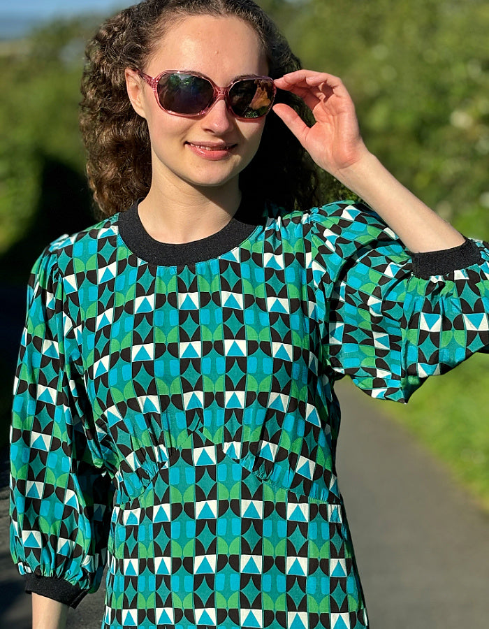 midi length dress with black and green and blue geo print and blouson sleeves