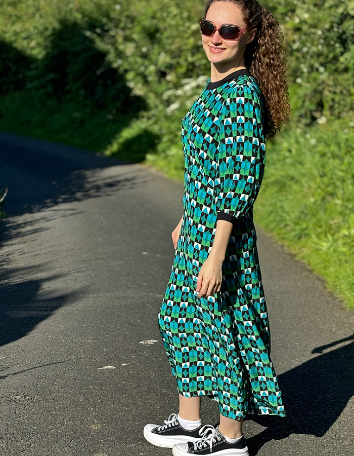 midi length dress with black and green and blue geo print and blouson sleeves