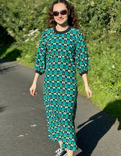 midi length dress with black and green and blue geo print and blouson sleeves