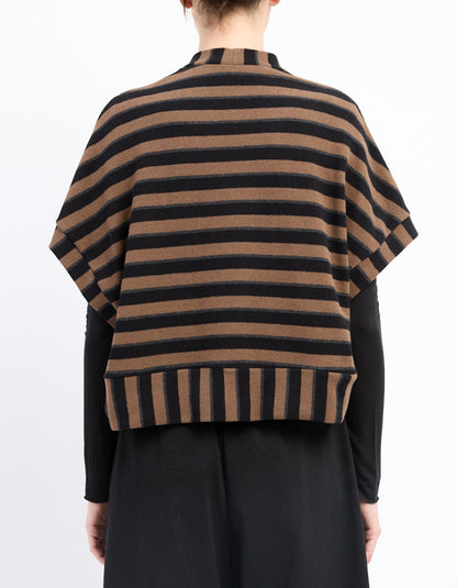 A person shown from the back wearing a brown and black horizontally striped knit poncho-style cardigan over a black long-sleeve top and black skirt, against a plain white studio background.