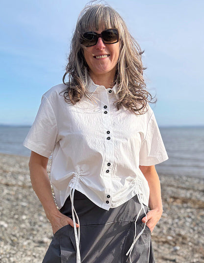 Woman wearing a white blouse with black buttons on a beach