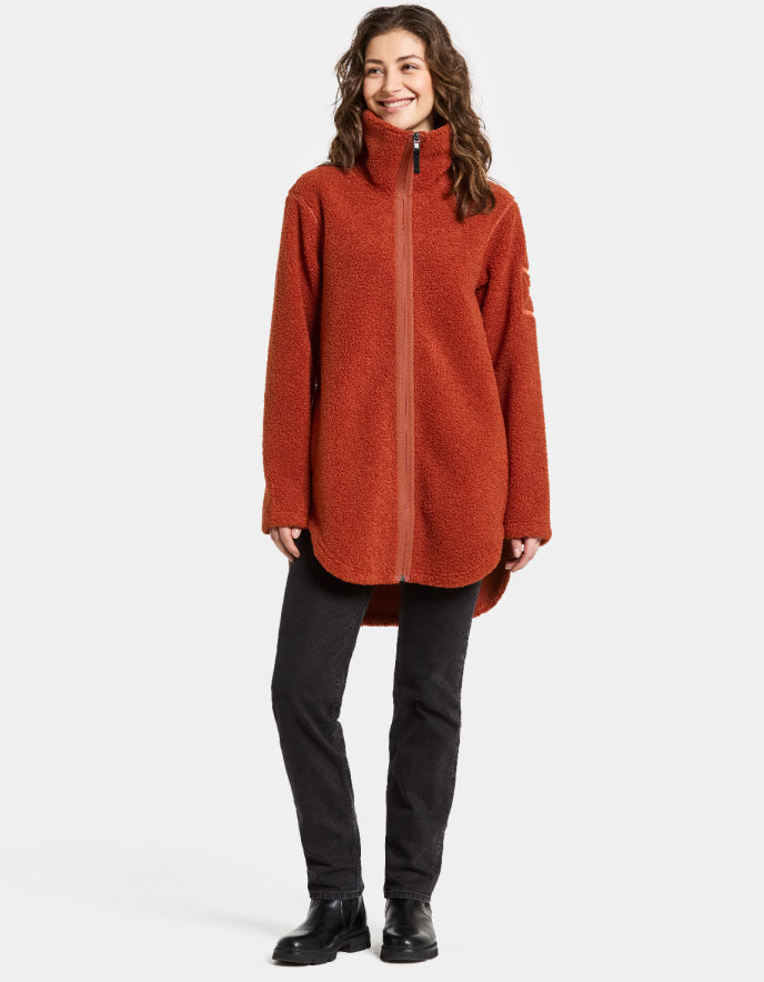 Woman wearing a rust orange sherpa pile fleece  jacket on a white background