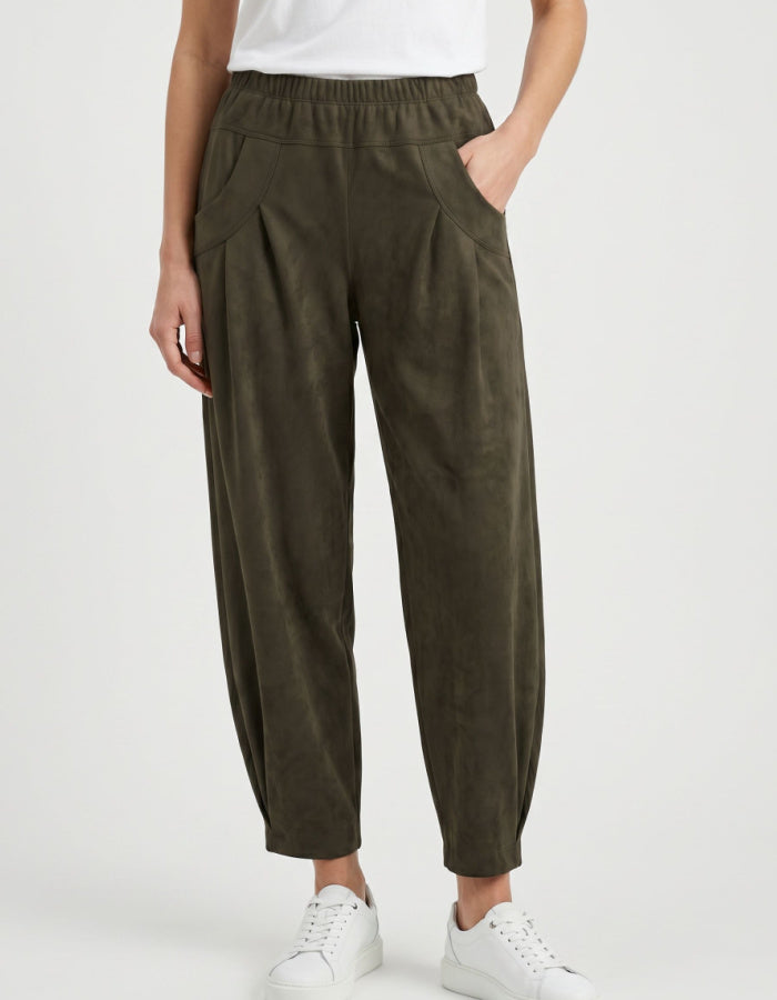 A person wearing dark olive green wide-leg cropped pants with an elastic waistband, side pockets, and a relaxed tapered leg, styled with a white top and white sneakers against a light gray studio background.