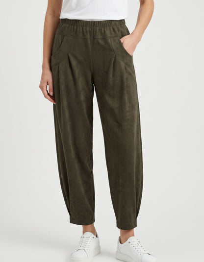 A person wearing dark olive green wide-leg cropped pants with an elastic waistband, side pockets, and a relaxed tapered leg, styled with a white top and white sneakers against a light gray studio background.