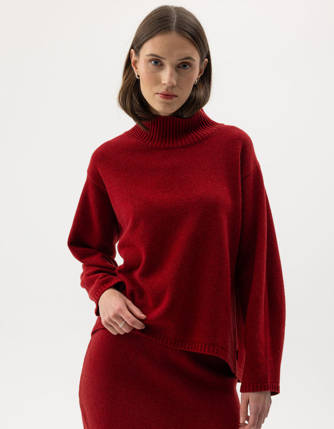 Woman wearing a red wool turtle neck sweater against a white background