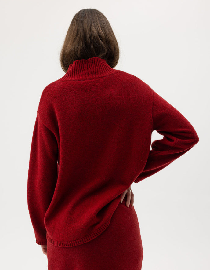 Woman wearing a red wool turtle neck sweater against a white background