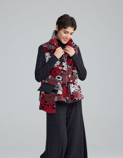 Person wearing a patterned red and black vest over a dark outfit on a light gray background