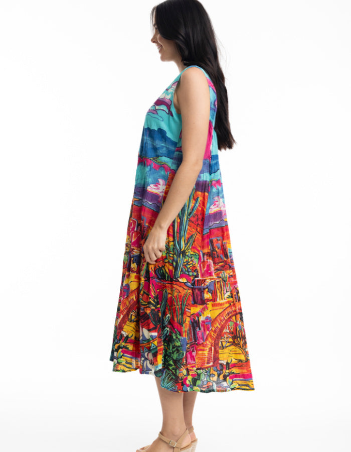 sleeveless sun dress made from crinkle cotton with v neckline and pockets and featuring a brightly coloured Mexican themed print