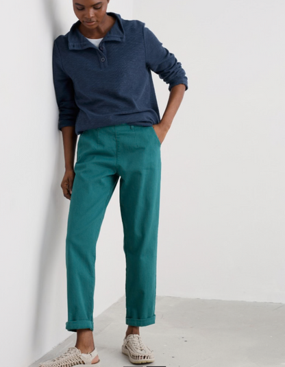 Person wearing a navy shirt and teal pants against a white background