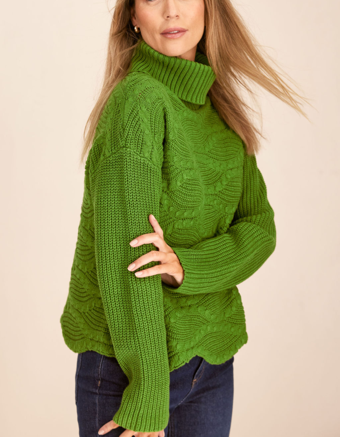 Person wearing a green knitted sweater on a beige background