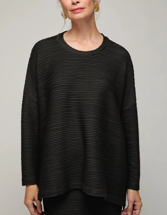 Woman wearing a black textured sweater against a plain background