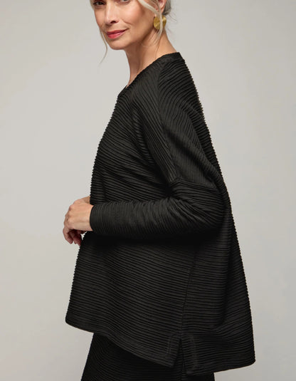 Woman wearing a black textured jacket against a plain background