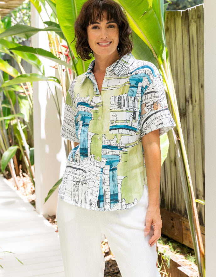 Woman wearing a patterned shirt standing outdoors with plants in the background