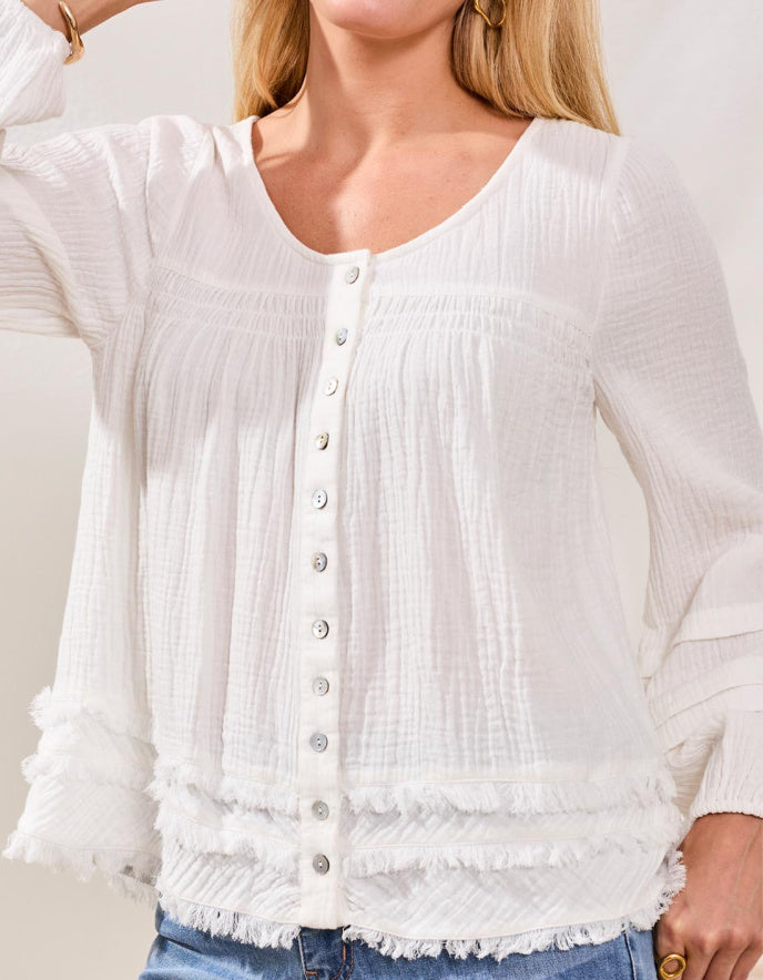 White textured blouse with buttons worn by a person, against a neutral background
