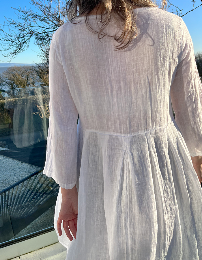 white linen dress with loose fit empire line shape and three quarter sleeves