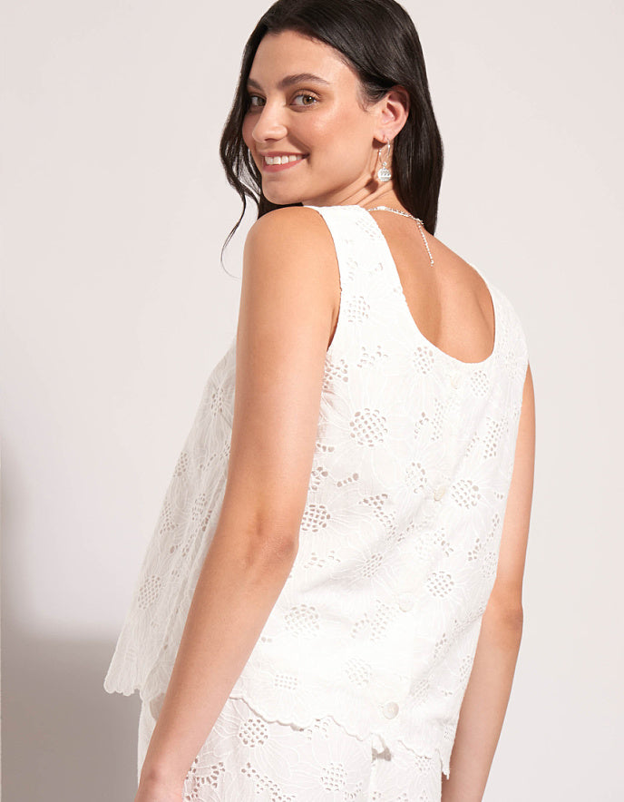 Woman wearing a white lace dress against a plain background