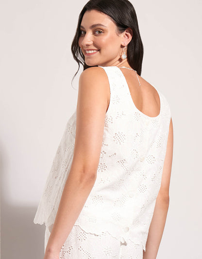 Woman wearing a white lace dress against a plain background